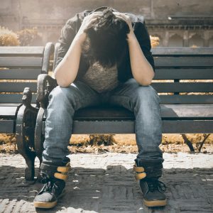 Man on bench showing signs of stress due to ED issues